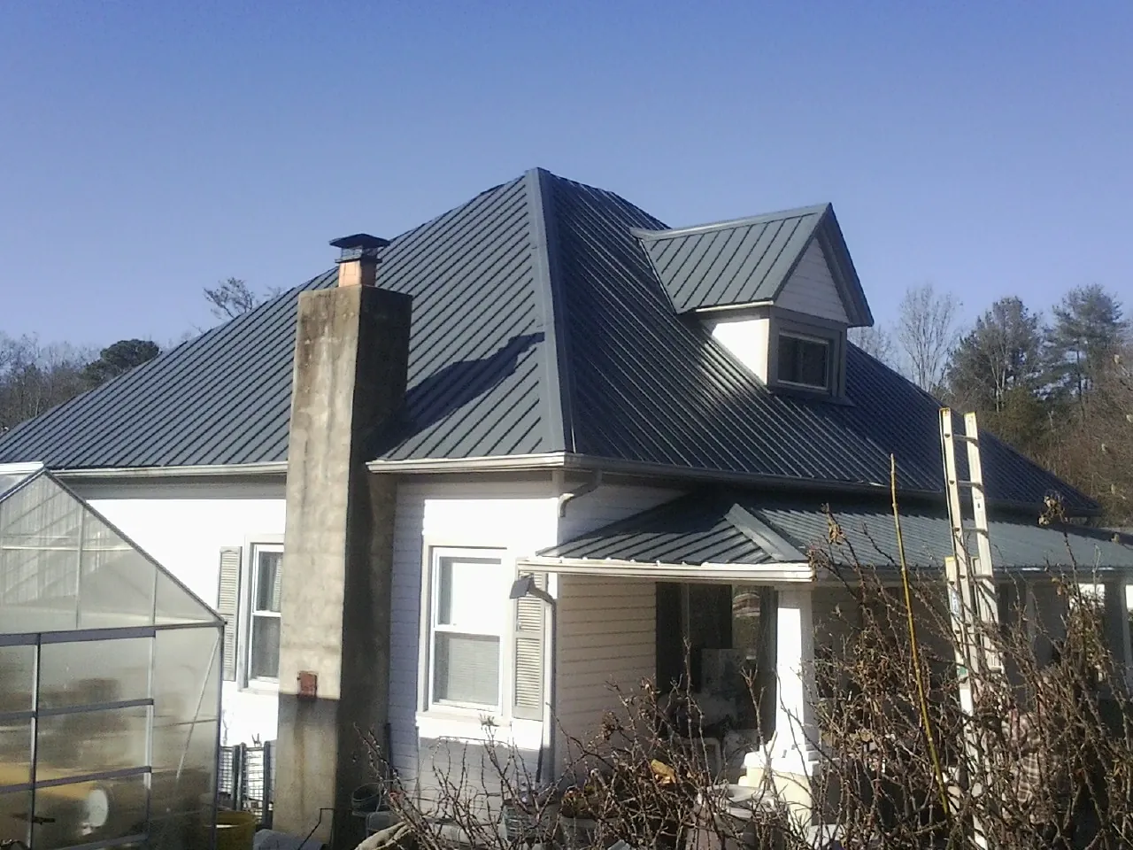 Dark blue standing seam metal roof on a white farmhouse with dormer — Slate & Tile Roof Repair by Roofing Brothers in Henning