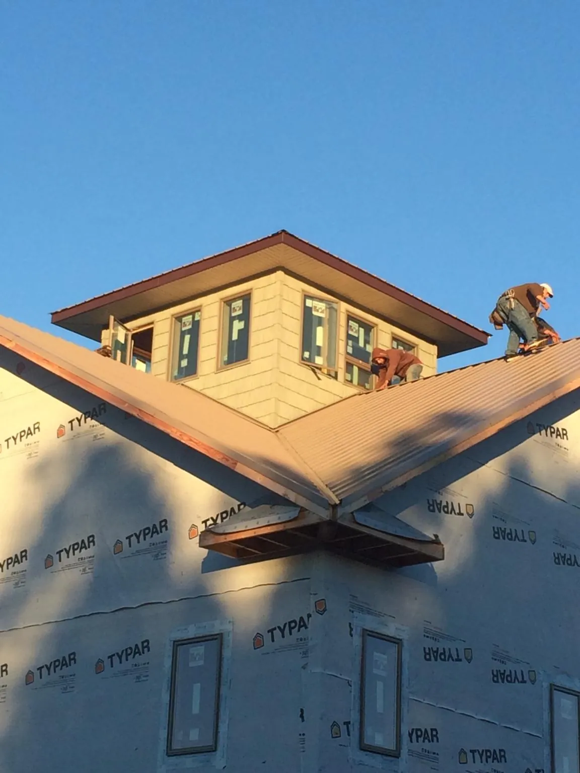 Roofers working around a rooftop cupola on a new metal roof at sunset — Roof Waterproofing in Henning by Roofing Brothers